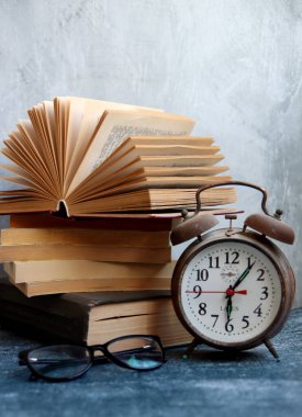 Masada eski kitaplarla dolu bir hayat. Vintage objeler, fotoğrafı kapatın. Fotokopi alanı olan gri arkaplan. Okuma konsepti zamanı. 