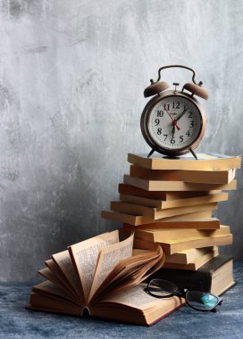 Bir yığın eski kitap, masanın üstünde antika bir saat. Açık gri desenli arkaplan ve kopyalama alanı. Eğitim kavramı. 