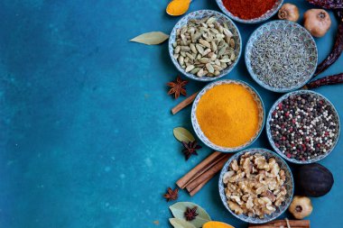 Masada farklı baharat ve bitkiler bulunan oryantal seramik tabaklar. Fotokopi alanı ile canlı mavi arkaplan. Güzel dekoratif tabaklar. Fotoğrafı kapat.. 