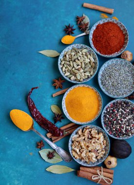 Masada farklı baharat ve bitkiler bulunan oryantal seramik tabaklar. Fotokopi alanı ile canlı mavi arkaplan. Güzel dekoratif tabaklar. Fotoğrafı kapat.. 
