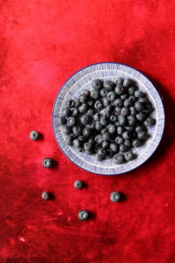 Süslü seramik tabakta yabanmersini. Böğürtlenli basit bir hayat. Kopyalama alanı olan desenli arkaplan.  