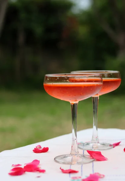 Two glasses of orange cocktail on a table. Romantic picnic in the garden. Summer drinks and beverages.