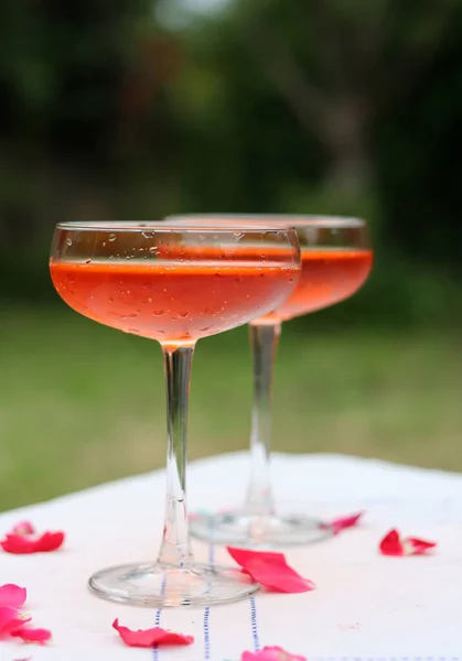 Two glasses of orange cocktail on a table. Romantic picnic in the garden. Summer drinks and beverages.