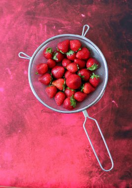 Süzgeçte sulu çilek. Kopya alanı ile kırmızı desenli arkaplan. Böğürtlenli basit kompozisyon. Sağlıklı konsept yemek. 