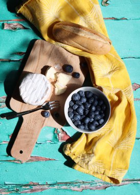 Taze yabanmersinli seramik kâse, ahşap tahtada kremalı peynir. Basit kompozisyon hala yaz yemekleriyle dolu.. 