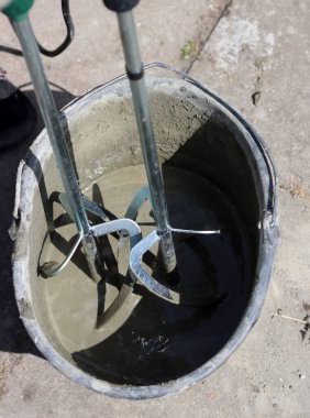 Taşınabilir beton karıştırıcı makinesi. Fotoğrafı kapat. Çimento dolu siyah bir kova. Kopyalama alanı olan gri arkaplan. 