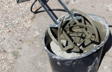 Taşınabilir beton karıştırıcı makinesi. Fotoğrafı kapat. Çimento dolu siyah bir kova. Kopyalama alanı olan gri arkaplan. 