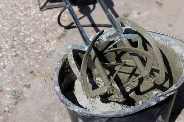 Taşınabilir beton karıştırıcı makinesi. Fotoğrafı kapat. Çimento dolu siyah bir kova. Kopyalama alanı olan gri arkaplan. 