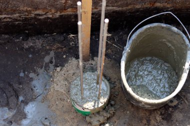 Dayanıklılık süreci devam ediyor. Bir kova beton, topraktaki takviye çelik. Ev yenileme konsepti. 