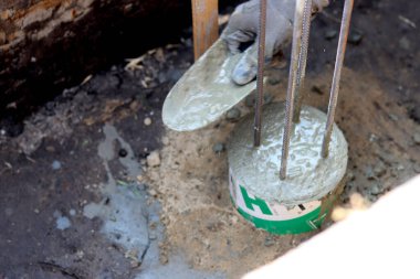 Dayanıklılık süreci devam ediyor. Bir kova beton, topraktaki takviye çelik. Ev yenileme konsepti. 