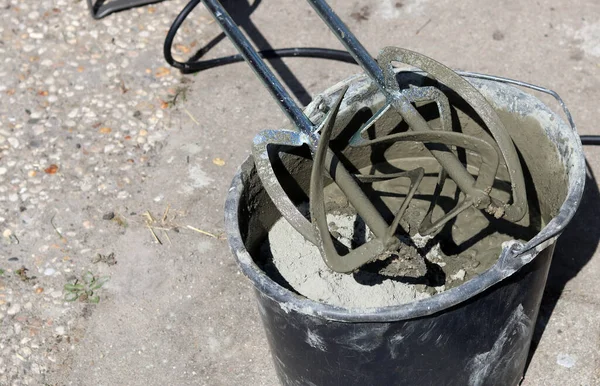 Taşınabilir beton karıştırıcı makinesi. Fotoğrafı kapat. Çimento dolu siyah bir kova. Kopyalama alanı olan gri arkaplan. 