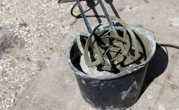 Taşınabilir beton karıştırıcı makinesi. Fotoğrafı kapat. Çimento dolu siyah bir kova. Kopyalama alanı olan gri arkaplan. 