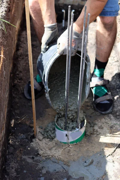 Cement work in progress. Foundation strength work. Bucket of concrete, reinforcement steel in a ground. House renovation concept.