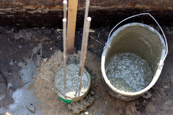 Dayanıklılık süreci devam ediyor. Bir kova beton, topraktaki takviye çelik. Ev yenileme konsepti. 