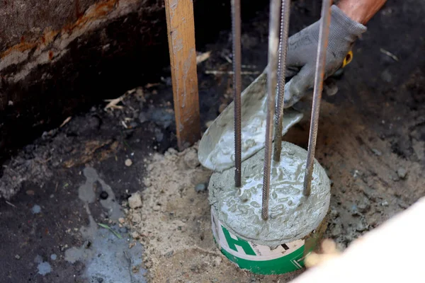 Dayanıklılık süreci devam ediyor. Bir kova beton, topraktaki takviye çelik. Ev yenileme konsepti. 