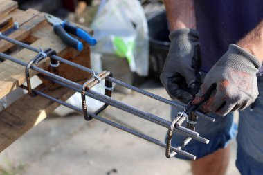 El ele tutuşan takviye çelik. Profesyonel inşaat işçisi. İnşaatçının koruyucu eldivenli ellerinin fotoğrafını çek.. 