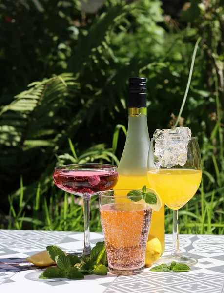 Refreshing summer cocktails on a garden table. Close up photo of glasses with various drinks. Party in a garden.