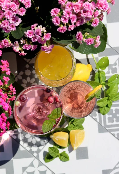 Mango, strawberry cocktails and rose lemonade on a garden table. Summer cocktails close up photo. Refreshing drinks in different glasses.