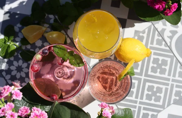 Mango, strawberry cocktails and rose lemonade on a garden table. Summer cocktails close up photo. Refreshing drinks in different glasses.