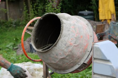 Concrete mixer close up photo. Construction worker equipment. Industrial cement mortar standing outdoors. 