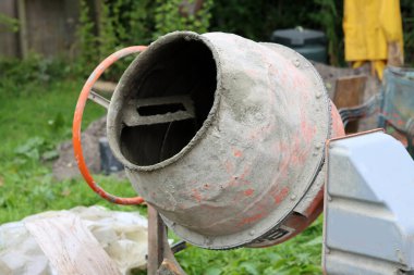 Concrete mixer close up photo. Construction worker equipment. Industrial cement mortar standing outdoors. 