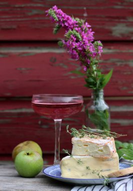 Still life with rose wine, brie cheese and bread on a table. French food concept. Summer picnic in the garden. 