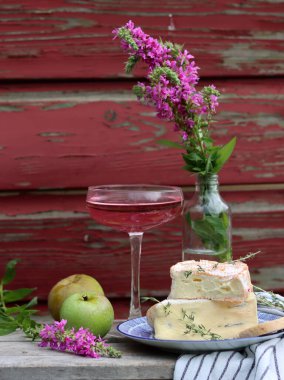 Still life with cheese and wine on a table. Delicious French cheese and glass of a pink wine. Colorful photo of tasty delicatessen.  