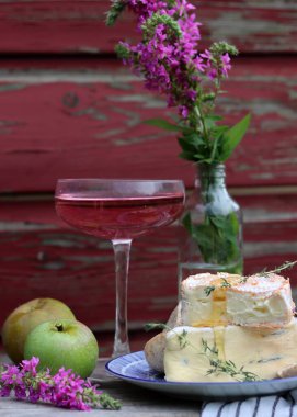 Still life with rose wine, brie cheese and bread on a table. French food concept. Summer picnic in the garden. 