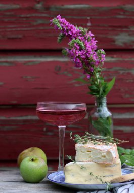 Still life with rose wine, brie cheese and bread on a table. French food concept. Summer picnic in the garden. 