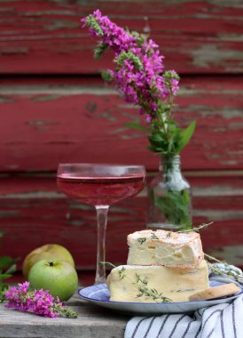 Still life with cheese and wine on a table. Delicious French cheese and glass of a pink wine. Colorful photo of tasty delicatessen.  
