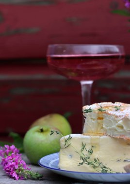 Still life with cheese and wine on a table. Delicious French cheese and glass of a pink wine. Colorful photo of tasty delicatessen.  
