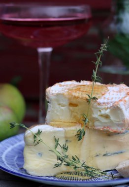 Still life with cheese and wine on a table. Delicious French cheese and glass of a pink wine. Colorful photo of tasty delicatessen.  