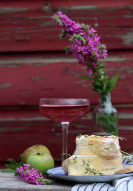 Still life with rose wine, brie cheese and bread on a table. French food concept. Summer picnic in the garden. 