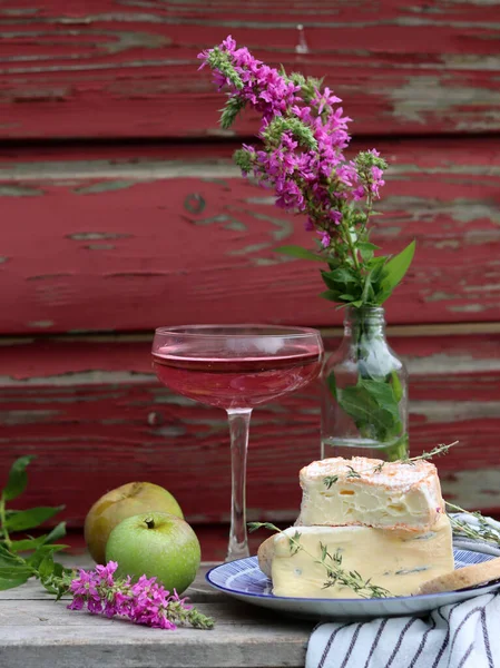 Still life with cheese and wine on a table. Delicious French cheese and glass of a pink wine. Colorful photo of tasty delicatessen.  