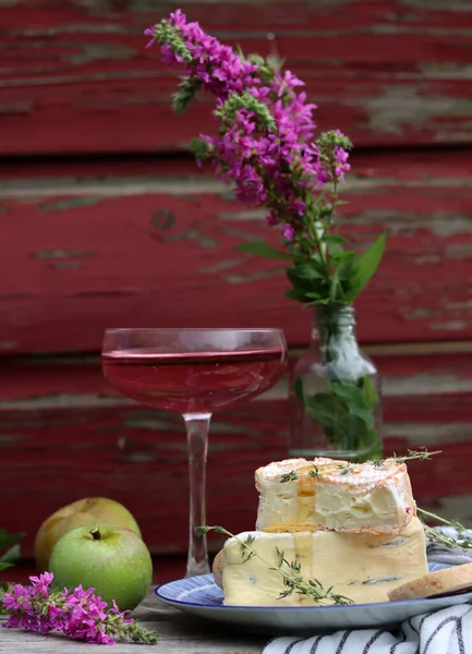 Still life with cheese and wine on a table. Delicious French cheese and glass of a pink wine. Colorful photo of tasty delicatessen.  