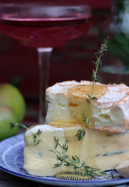 Still life with cheese and wine on a table. Delicious French cheese and glass of a pink wine. Colorful photo of tasty delicatessen.  