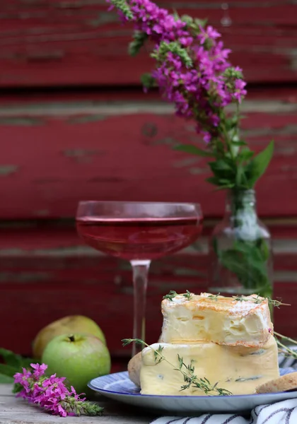 Still life with rose wine, brie cheese and bread on a table. French food concept. Summer picnic in the garden. 