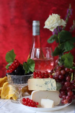 Still life with cheese and wine on a table. Delicious French cheese and glass of a pink wine. Colorful photo of tasty delicatessen.  