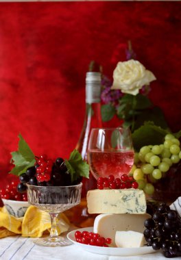 Still life with cheese and wine on a table. Delicious French cheese and glass of a pink wine. Colorful photo of tasty delicatessen.  