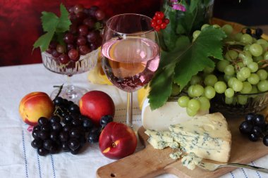 Still life with cheese and wine on a table. Delicious French cheese and glass of a pink wine. Colorful photo of tasty delicatessen.  