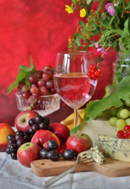 Camembert cheese, green and black grapes, glass of rose wine on a table. Colorful summer still life with seasonal fruit and berries. 