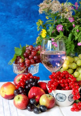 Wine and fruit on a table. Beautiful composition of juicy berries, grapes and rose wine. Harvest celebration. Textured background with copy space. 