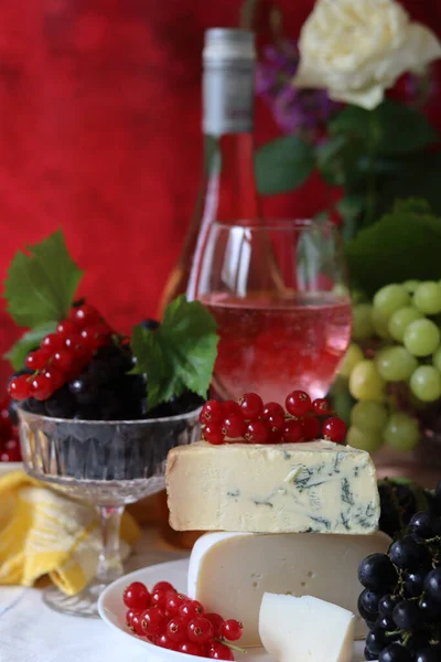 Still life with cheese and wine on a table. Delicious French cheese and glass of a pink wine. Colorful photo of tasty delicatessen.  