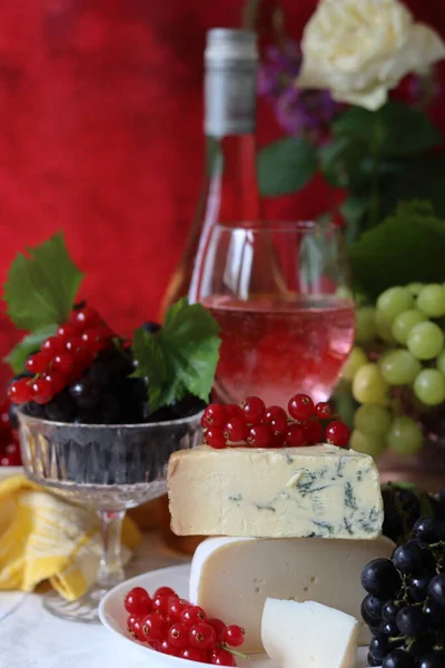 Still life with cheese and wine on a table. Delicious French cheese and glass of a pink wine. Colorful photo of tasty delicatessen.