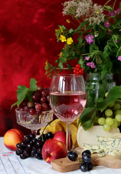 Still life with cheese and wine on a table. Delicious French cheese and glass of a pink wine. Colorful photo of tasty delicatessen.  