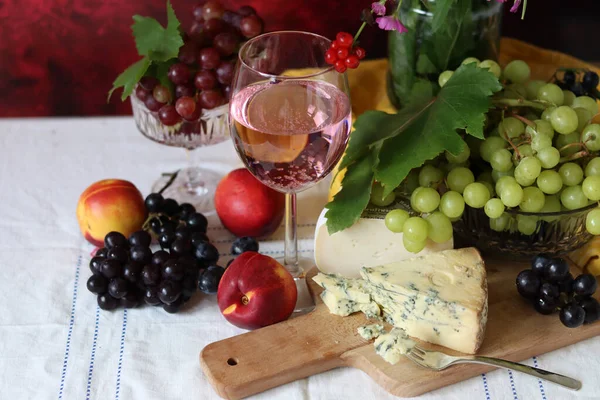 Still life with cheese and wine on a table. Delicious French cheese and glass of a pink wine. Colorful photo of tasty delicatessen.  