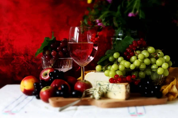 Wine and fruit on a table. Beautiful composition of juicy berries, grapes and rose wine. Harvest celebration. Textured background with copy space. 