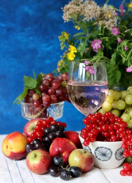 Wine and fruit on a table. Beautiful composition of juicy berries, grapes and rose wine. Harvest celebration. Textured background with copy space. 