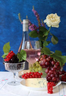 Grapes, wine and cheese on a table. Colorful summer still life on textured background with copy space.