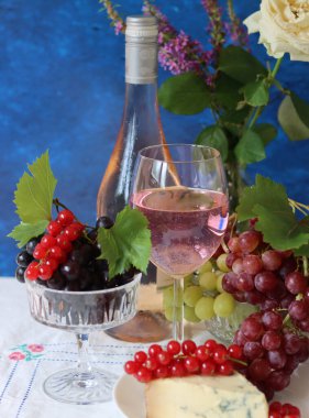 Grapes, wine and cheese on a table. Colorful summer still life on textured background with copy space.